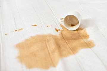 Spilled coffee on white fabric unattended cup creates stain