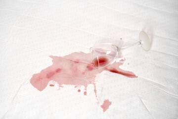 Red wine spill on white fabric with glass tipped over