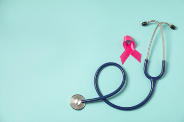 Breast cancer awareness. Pink ribbon and stethoscope on light blue background, flat lay. Space for text