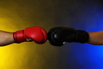 Men in boxing gloves fighting on dark background with smoke, closeup
