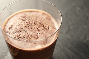 Tasty chocolate milk with shavings on black table, closeup
