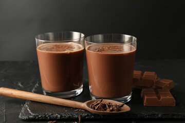 Tasty chocolate milk with shavings and pieces on black table
