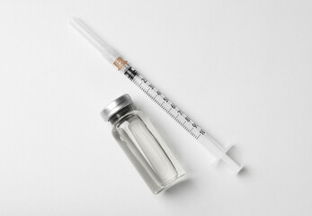 Hepatitis vaccine in glass vial and syringe on white background, top view