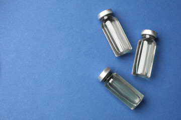 Naklejka premium Hepatitis vaccine in glass vials on blue background, flat lay. Space for text