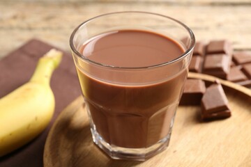 Tasty chocolate milk, pieces and banana on table, closeup
