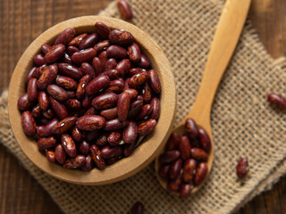 Red kidney beans in a scoop on a wooden table against a white background.