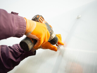 A man assembles a new greenhouse from polyethylene and polycarbonate
