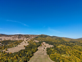 Scenic panorama of peaceful countryside in Romania with green hills, mountains, and autumn forest.