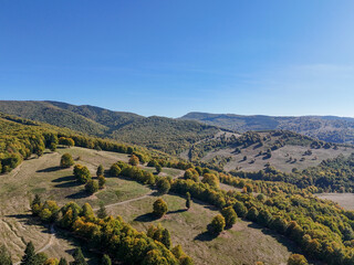 Scenic panorama of peaceful countryside in Romania with green hills, mountains, and autumn forest.