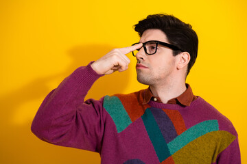 Young handsome man with glasses making a thoughtful gesture in front of a bright yellow background...