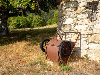 rusty bucket on wheels near old stone hut on hills in the Southern Alps in France
