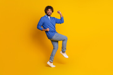 Fototapeta premium Young stylish male posing in a blue polo shirt with a vibrant yellow background conveying energy and modern style