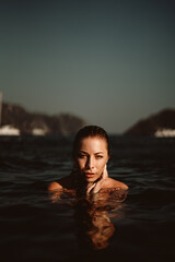 Fototapeta premium A beautiful girl posing in the sea, exuding fashion and elegance as she showcases her style in the water.