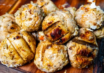 Grilled meatballs served on wooden board with herbs and spices