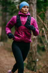 Determined Female Athlete Running with Focus Through a Dense Pine Forest, Embracing Strength and Nature