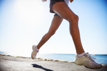 Person, legs and running on road training for marathon practice for healthy cardio, competition or exercise. Athlete, sneakers and jog on street for outdoor physical commitment or speed, path or race