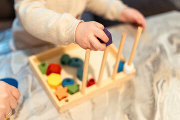 Child engages in colorful shape sorting activity on a wooden tray at home during the afternoon