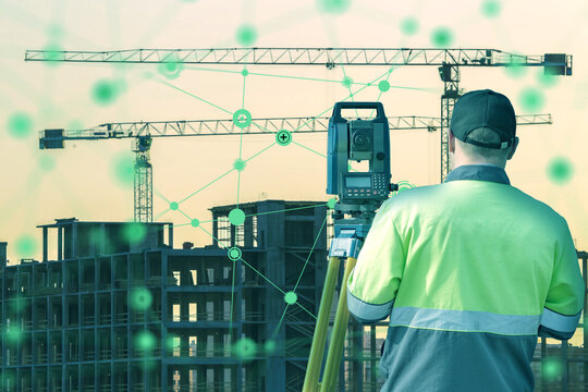 Surveyor with a total station collects geospatial data at a building site with cranes and digital overlay. Scene relates to smart construction and civil engineering.