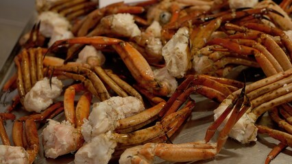 Cooked crab legs showing delicious white meat lying on metal tray