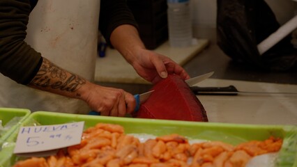 Fishmonger slicing fresh tuna steak at the fish market