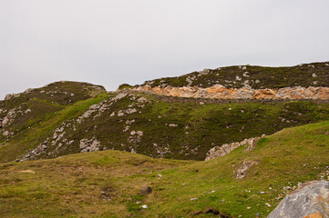 A rocky hillside with a grassy area in the middle