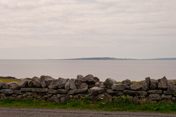 A wall of rocks is on the side of a road