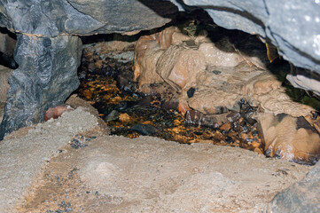 A small stream of water flows through a rocky cave