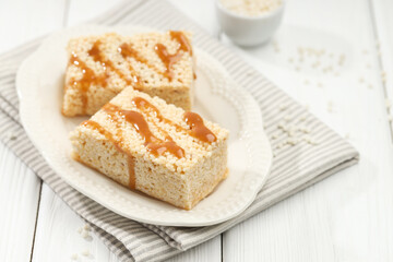 Delicious caramel puffed rice bars on white wooden table, closeup