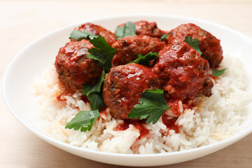 Delicious meatballs with rice, sauce and parsley on light wooden table, closeup