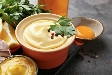 Delicious mayonnaise sauce in bowl and ingredients on grey table, closeup