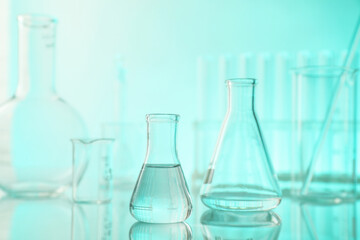 Laboratory glassware on mirror surface against turquoise background