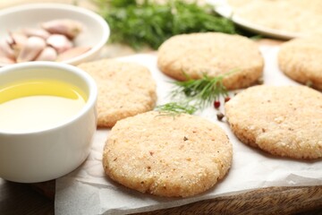 Many uncooked patties and spices on table, closeup