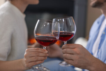 Couple clinking glasses of wine at home, selective focus