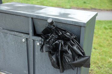 Broken black umbrella in garbage bin outdoors