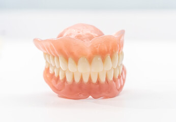Close-up of a dental prosthetic model with artificial teeth and gums on a wooden surface. Ideal for dental care imagery