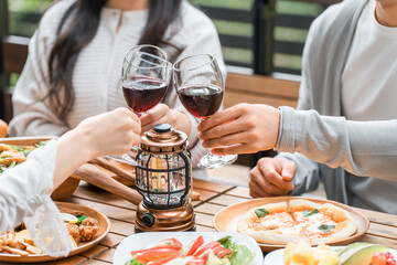 ウッドデッキでホームパーティー・グランピングする若いアジア人男女グループ
