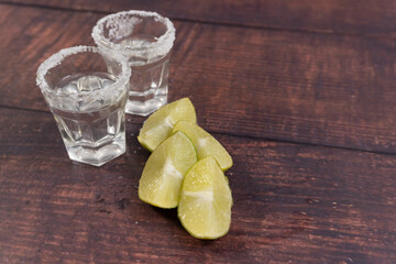 Pair of tequila glasses rimmed with salt and lemon slices on a wooden table