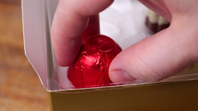 Picking red chocolate candy from box in slow motion