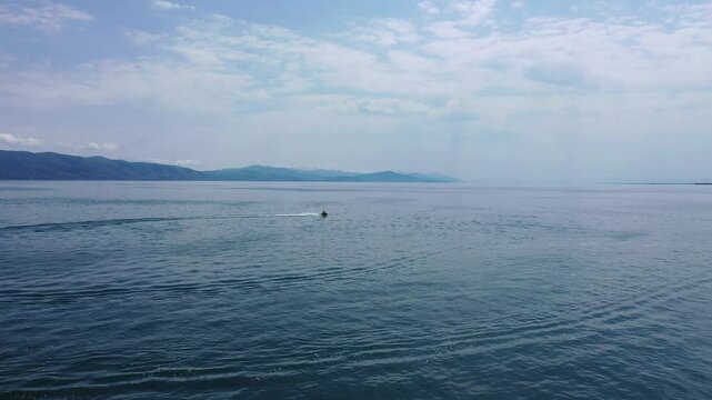 Wide, scenic view of Lake Sevan, Armenia, featuring a jet ski moving across the wate