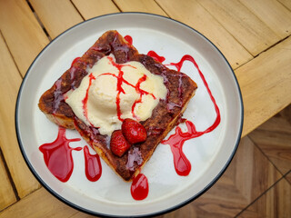 Toast with vanilla ice cream topped with strawberry syrup and fresh strawberries. Healthy delicious breakfast. French toast with ice cream. Restaurant food.