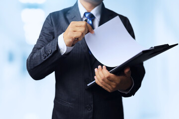 Businessman standing and opening A4 paper in black document folder to check information or content and study details before agreeing or approving.