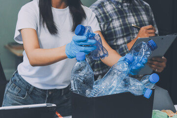 Close-up of female hands from a family collecting plastic waste and bottles from the ground. They...