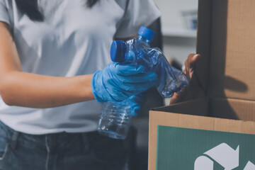 Close-up of female hands from a family collecting plastic waste and bottles from the ground. They...
