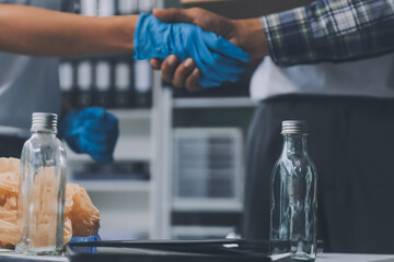 Close-up of female hands from a family collecting plastic waste and bottles from the ground. They wear gloves and focus on recycling to help reduce plastic pollution and protect the environment.