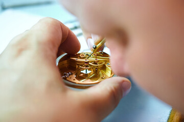 Expert craftsmanship shines as a man meticulously repairs a classic watch in a cozy workshop filled...