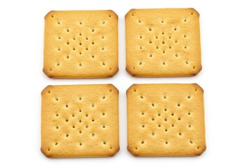 Four square crackers arranged on a white surface with small holes evenly distributed on each cracker