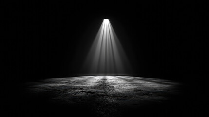 A dimly lit space with a single beam of light illuminating the ground, creating a dramatic contrast against the surrounding darkness.