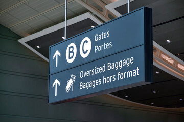 Bilingual Airport Direction Sign for Gates and Oversized Baggage in Modern Terminal