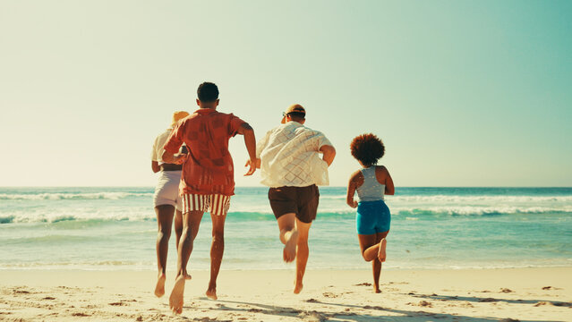 Friends, back and running at beach, vacation and social in summer, waves and outdoor on adventure. People, group and together on holiday on island, nature and playful in sunshine on getaway by ocean