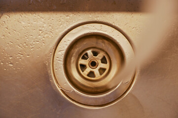Close-up of water draining from a kitchen sink in early afternoon